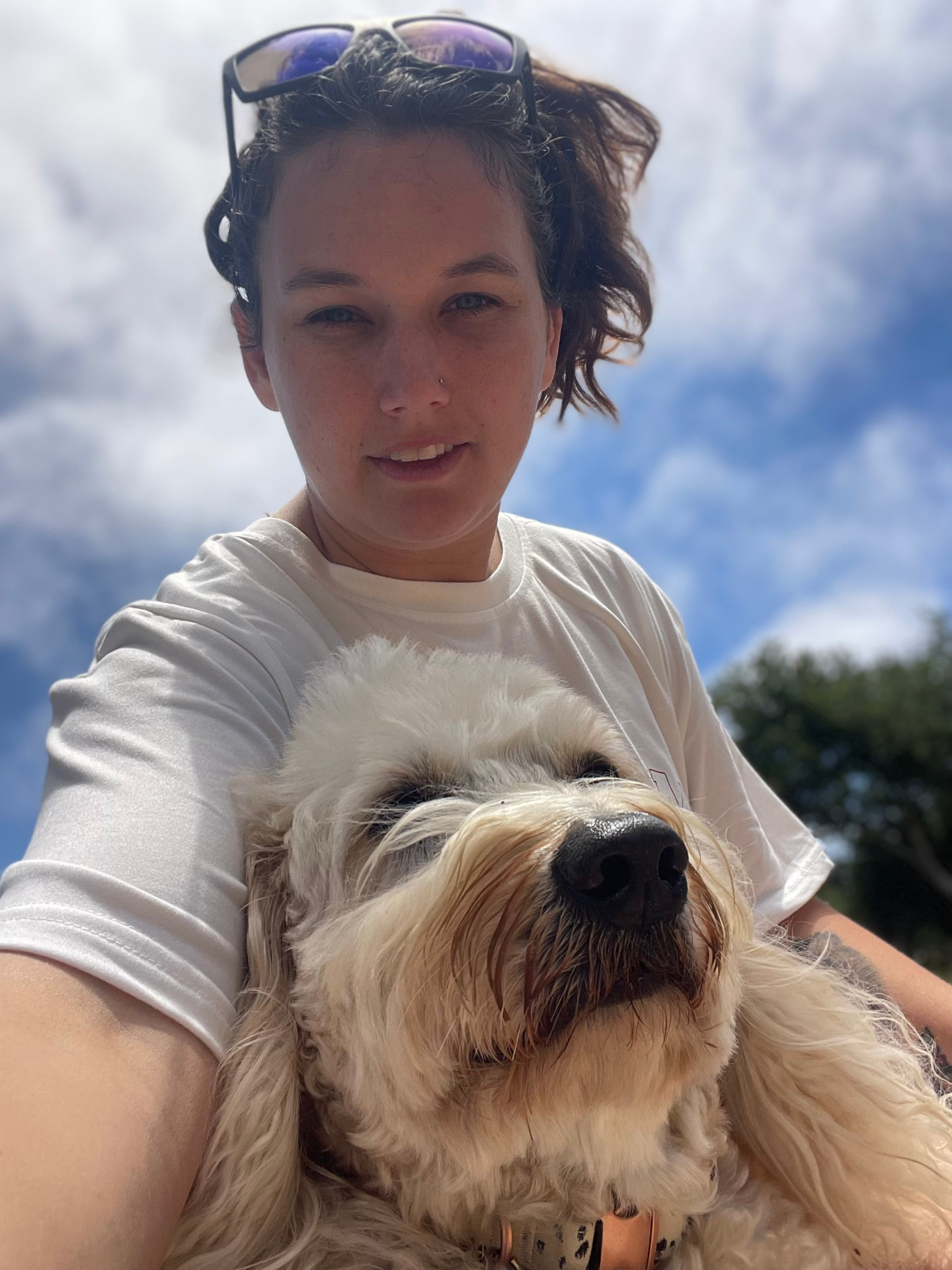 Avela, Certified Veterinary Assistant and Ventura County pet sitter, outdoors holding a happy fluffy dog